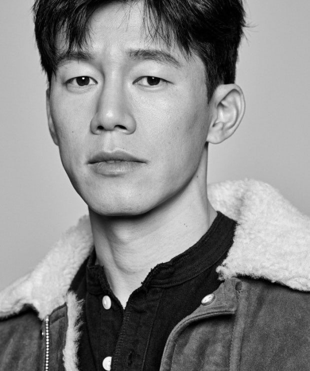 Retrato en primer plano y en blanco y negro del actor Kim Mu-yeol vistiendo una chaqueta con cuello de borrego.