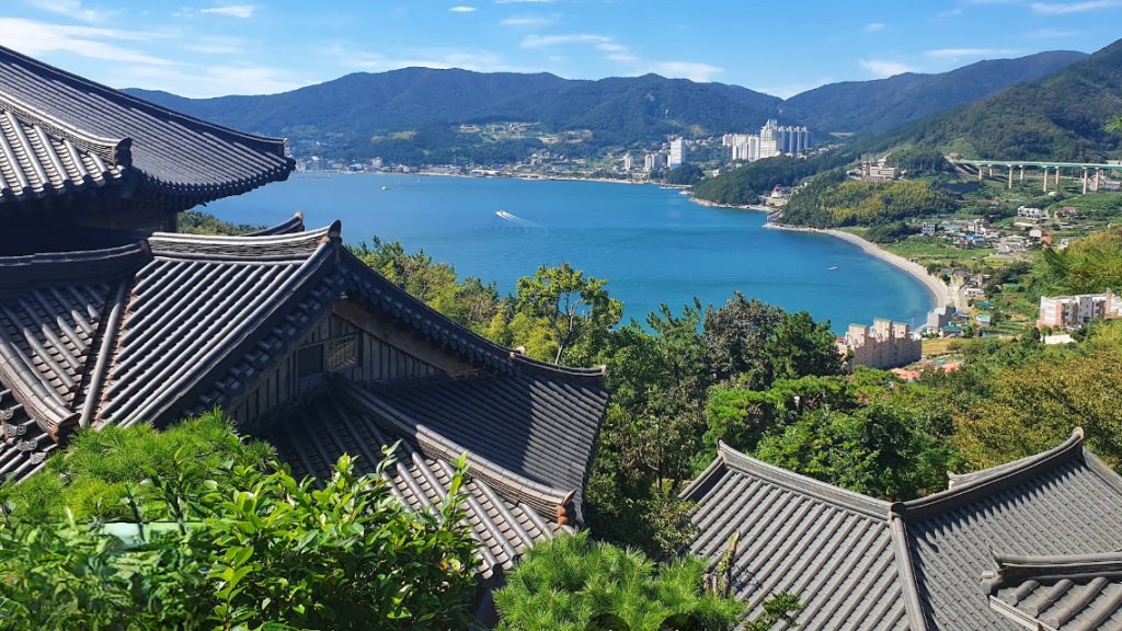 Vista panorámica desde la Pensión Sonang-gu en Geoje, mostrando los tejados tradicionales coreanos con el mar y las montañas de fondo.